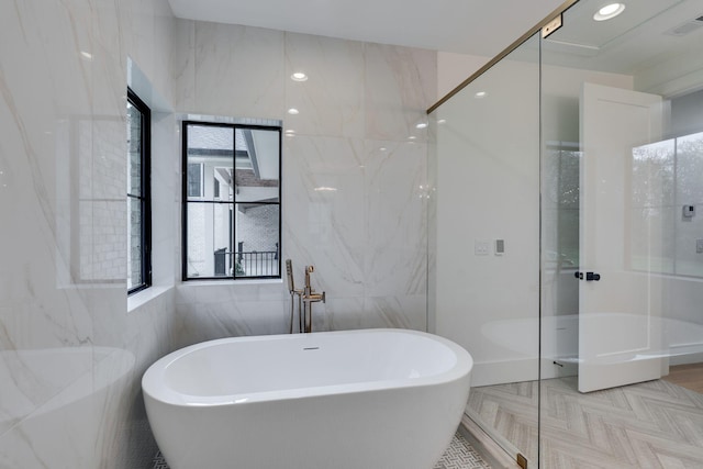 bathroom featuring tile walls, walk in shower, visible vents, and a freestanding bath