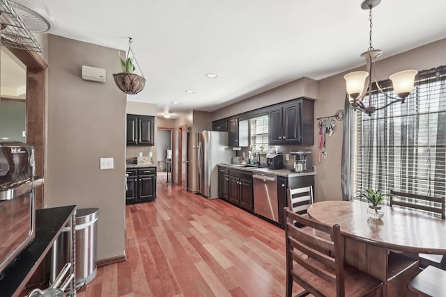 kitchen featuring recessed lighting, an inviting chandelier, a sink, light wood-type flooring, and appliances with stainless steel finishes