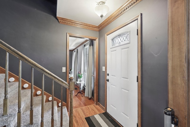 foyer with stairway, baseboards, crown molding, and light wood-style floors