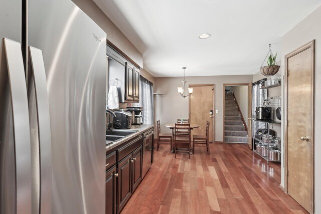 kitchen with light countertops, a sink, light wood-type flooring, hanging light fixtures, and appliances with stainless steel finishes