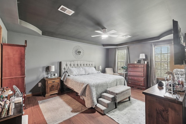 bedroom with baseboards, a ceiling fan, wood finished floors, and visible vents