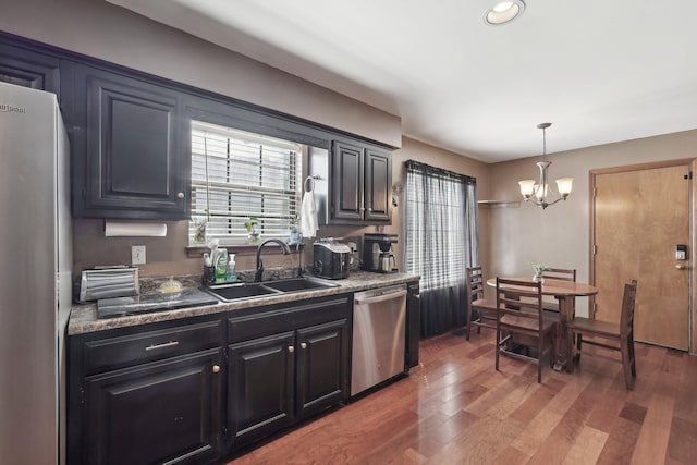 kitchen with light wood-style flooring, a sink, freestanding refrigerator, an inviting chandelier, and dishwasher