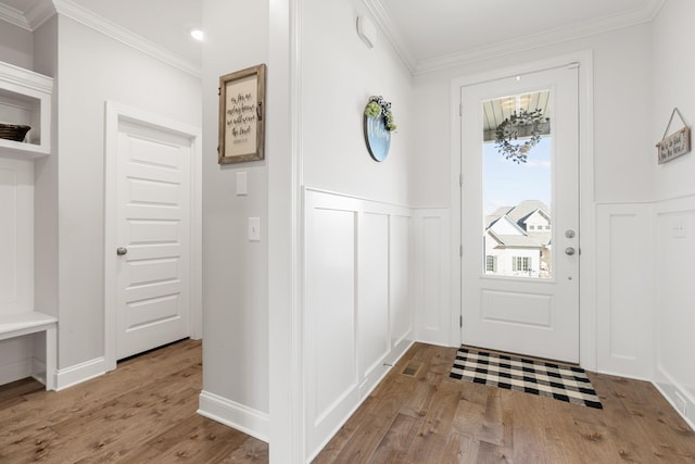 entryway featuring a wainscoted wall, wood finished floors, a decorative wall, and crown molding