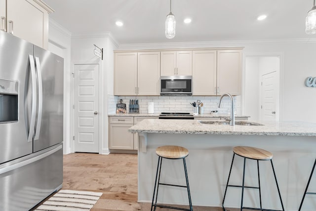 kitchen with stainless steel appliances, a sink, crown molding, light wood-style flooring, and a breakfast bar area