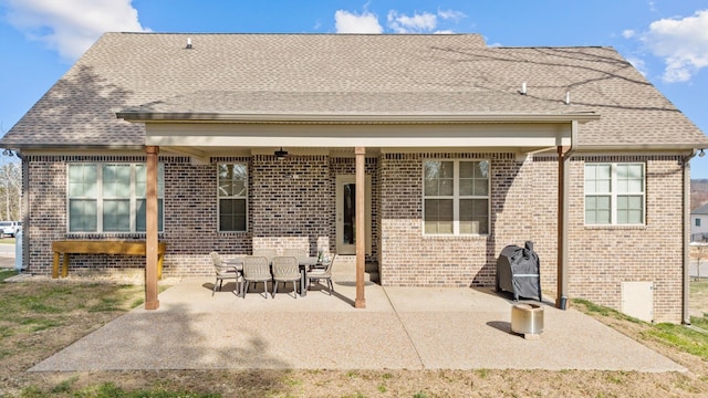 rear view of house with brick siding, a patio, and a shingled roof