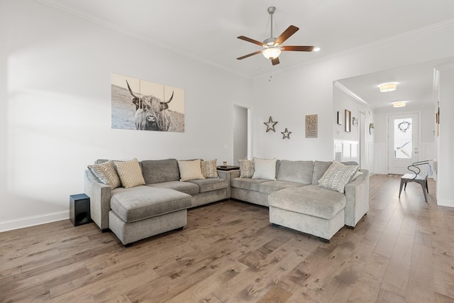 living area featuring baseboards, a ceiling fan, wood finished floors, and ornamental molding