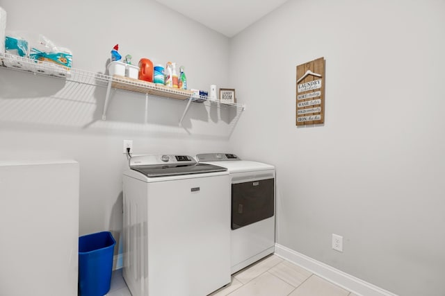washroom with light tile patterned floors, baseboards, separate washer and dryer, and laundry area