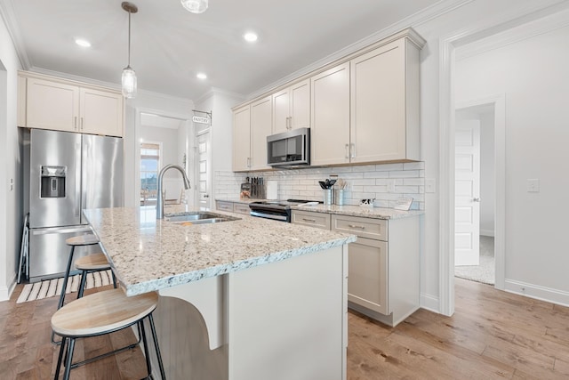 kitchen featuring a kitchen breakfast bar, a sink, decorative backsplash, light wood-style flooring, and appliances with stainless steel finishes