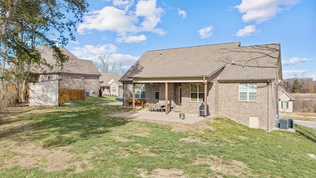 rear view of house with brick siding, a patio area, a lawn, and central air condition unit