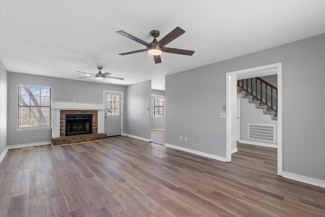 unfurnished living room with wood finished floors, baseboards, plenty of natural light, and a textured ceiling
