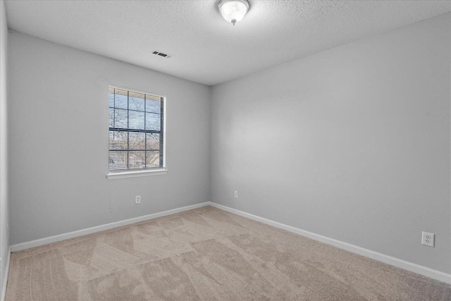 empty room with carpet floors, a textured ceiling, and baseboards