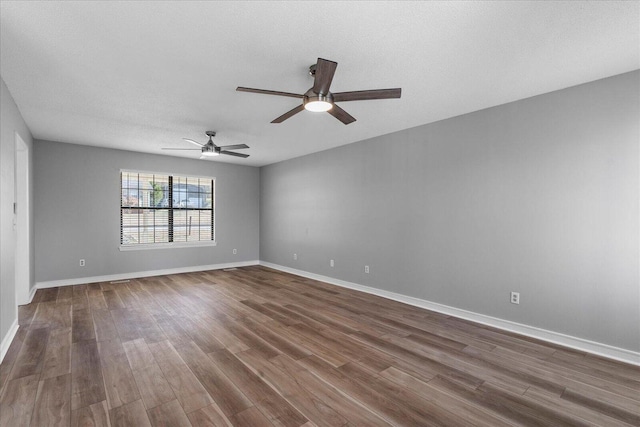 unfurnished room featuring dark wood-style floors, ceiling fan, and baseboards