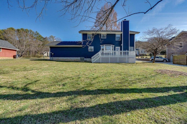 view of front facade with a chimney, a wooden deck, and a front yard