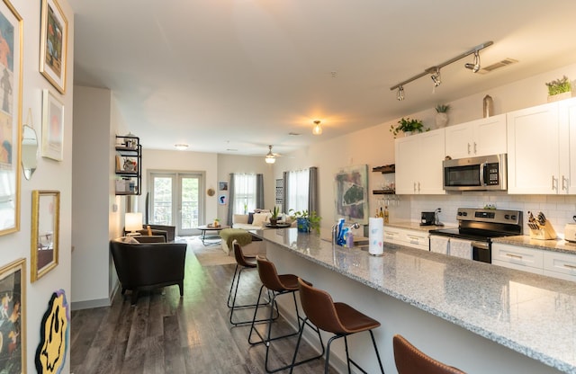 782 Riverfront Pkwy Unit 301, Chattanooga, TN 37402 - kitchen featuring a kitchen breakfast bar, open floor plan, backsplash, white cabinetry, and appliances with stainless steel finishes