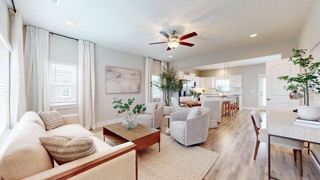 living room with ceiling fan, light wood-type flooring, recessed lighting, and baseboards