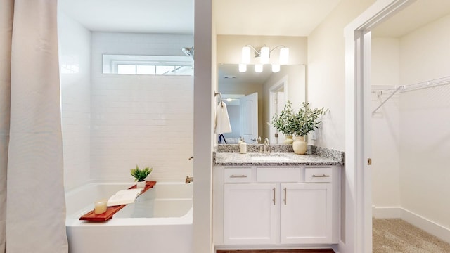 full bath with vanity, a spacious closet, and baseboards