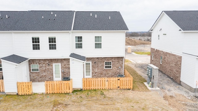 back of house featuring fence and brick siding