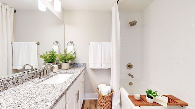 full bathroom featuring wood finished floors, vanity, shower / tub combo with curtain, and baseboards