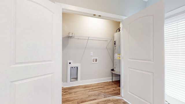 clothes washing area with hookup for a washing machine, light wood-style floors, electric dryer hookup, water heater, and baseboards