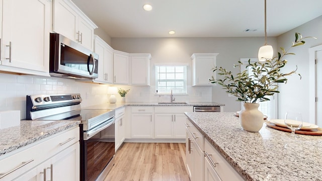 kitchen featuring white cabinets, stainless steel appliances, light wood-style flooring, and a sink