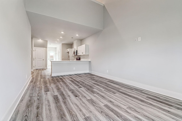 unfurnished living room with baseboards, light wood finished floors, and recessed lighting