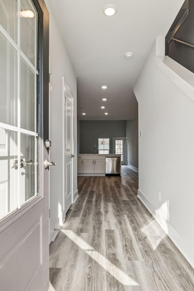 hallway featuring recessed lighting, wood finished floors, and a sink