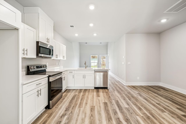kitchen with recessed lighting, visible vents, a sink, a peninsula, and appliances with stainless steel finishes