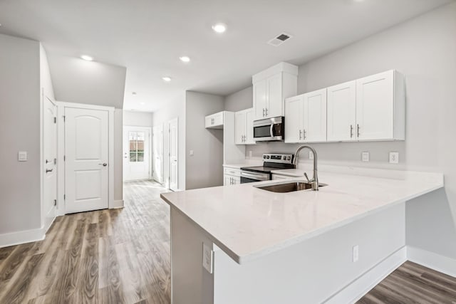 kitchen with wood finished floors, visible vents, a sink, baseboards, and appliances with stainless steel finishes