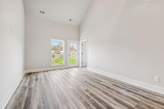 unfurnished room featuring high vaulted ceiling, baseboards, wood finished floors, and visible vents