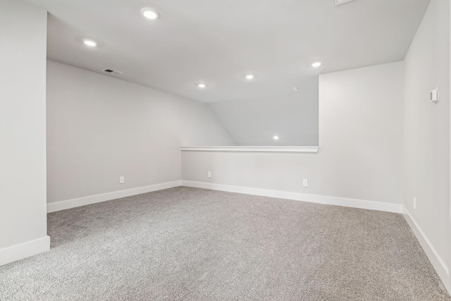 carpeted spare room featuring recessed lighting, vaulted ceiling, visible vents, and baseboards