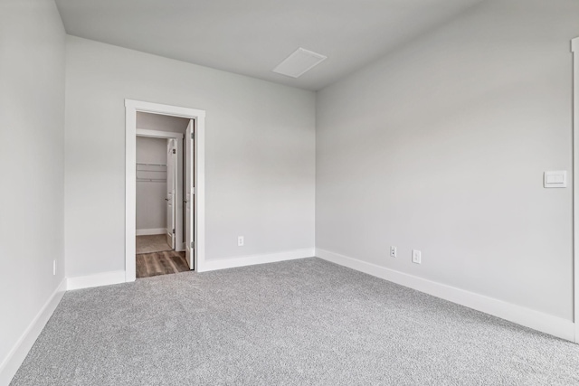 unfurnished bedroom featuring carpet floors, a spacious closet, and baseboards