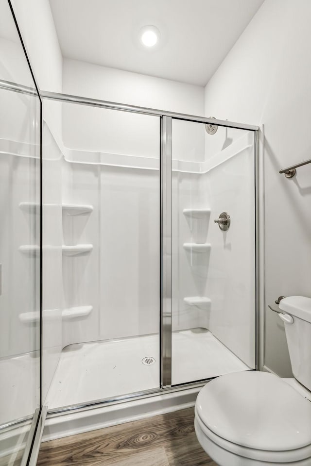 bathroom featuring a stall shower, wood finished floors, and toilet