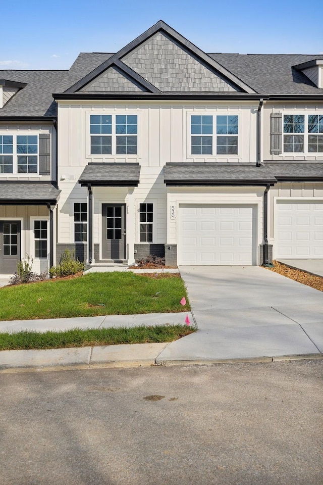 view of property featuring a shingled roof, a front lawn, board and batten siding, driveway, and a garage