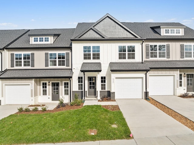 multi unit property with board and batten siding, a shingled roof, driveway, and a front lawn
