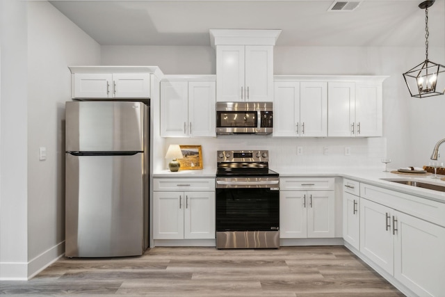 kitchen featuring white cabinets, visible vents, a sink, decorative backsplash, and appliances with stainless steel finishes