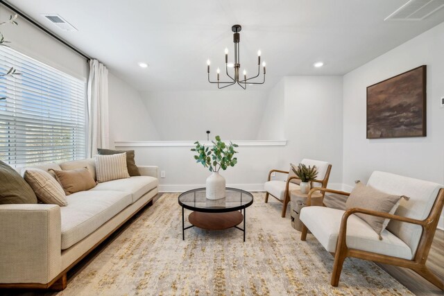 living area featuring baseboards, wood finished floors, a chandelier, and visible vents