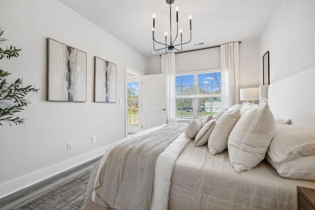 bedroom with baseboards, wood finished floors, and an inviting chandelier