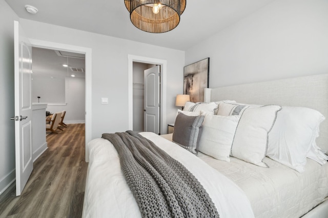 bedroom featuring attic access, baseboards, wood finished floors, and visible vents