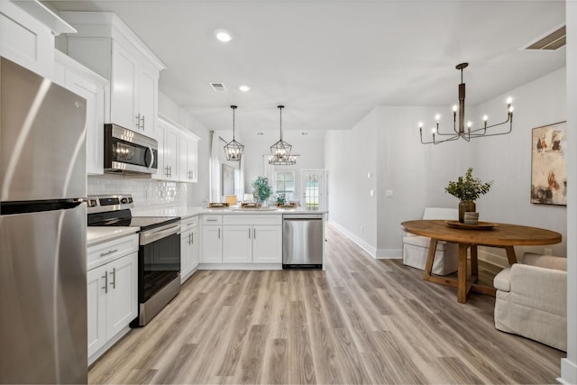 kitchen with an inviting chandelier, light countertops, visible vents, a peninsula, and appliances with stainless steel finishes