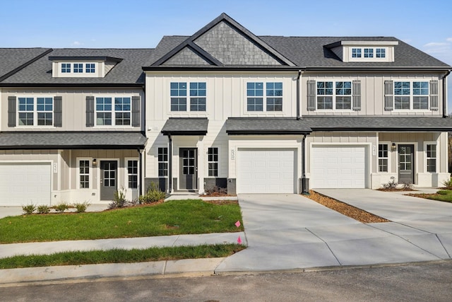 view of property featuring a front lawn, driveway, board and batten siding, a garage, and roof with shingles