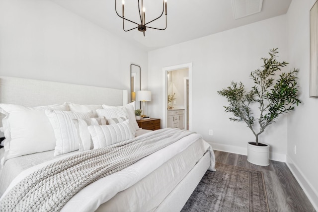bedroom with visible vents, baseboards, a notable chandelier, wood finished floors, and ensuite bath