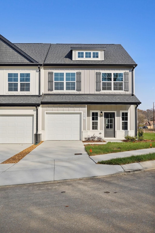 view of property with an attached garage, driveway, and a shingled roof