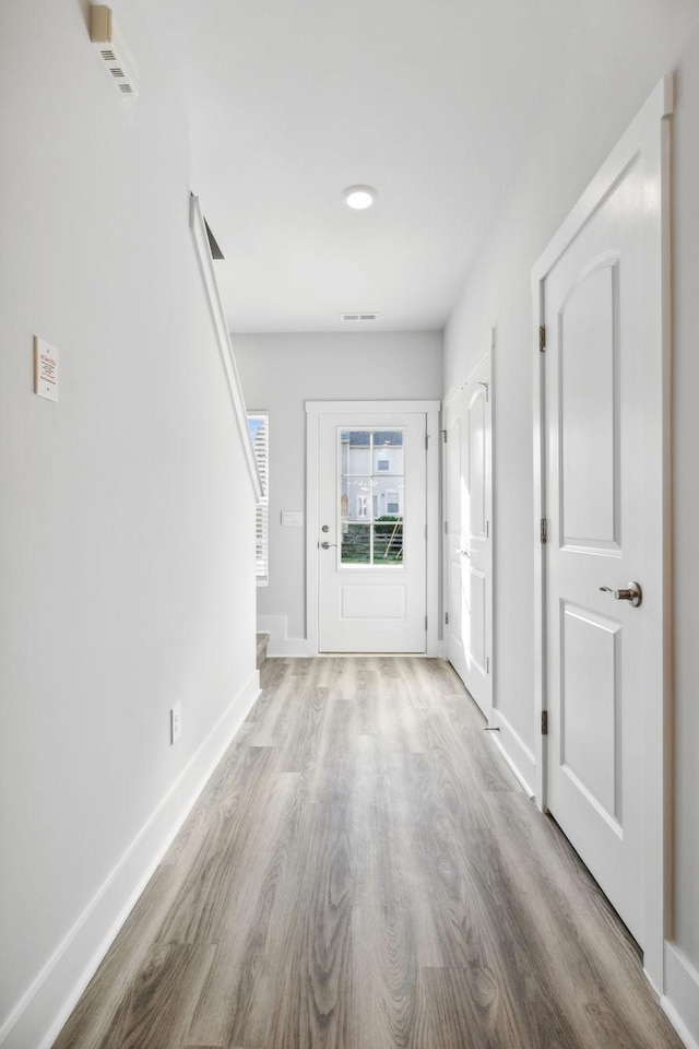 foyer entrance with wood finished floors, visible vents, baseboards, and stairway