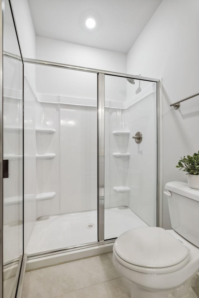 bathroom featuring a shower stall, toilet, and tile patterned floors