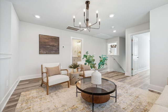 sitting room featuring baseboards, a notable chandelier, wood finished floors, and an upstairs landing