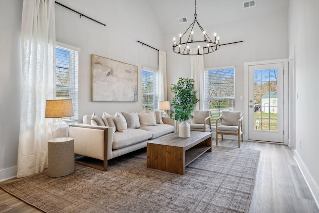 living area featuring visible vents, wood finished floors, a high ceiling, and a chandelier