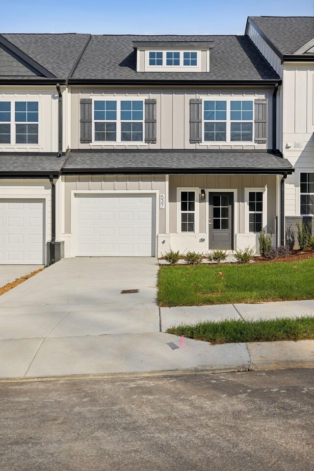 townhome / multi-family property with driveway, roof with shingles, and a garage