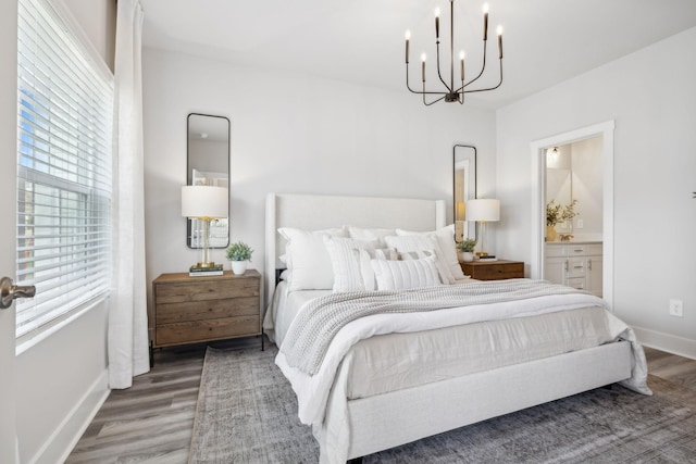 bedroom with a chandelier, wood finished floors, baseboards, and ensuite bathroom