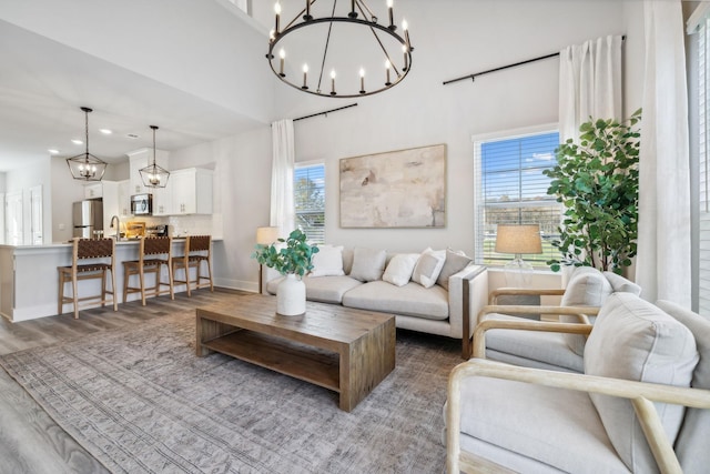 living room with baseboards, a notable chandelier, wood finished floors, and a healthy amount of sunlight