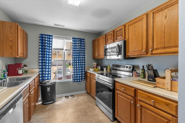 9051 Haileys Pond Dr, Ooltewah, TN 37363 - kitchen featuring a sink, visible vents, brown cabinets, light countertops, and appliances with stainless steel finishes
